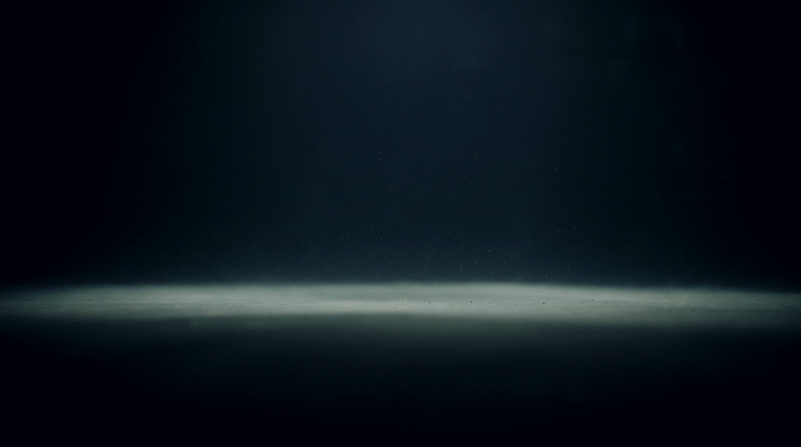 A perfectly level plane of pale light resting in still dark water